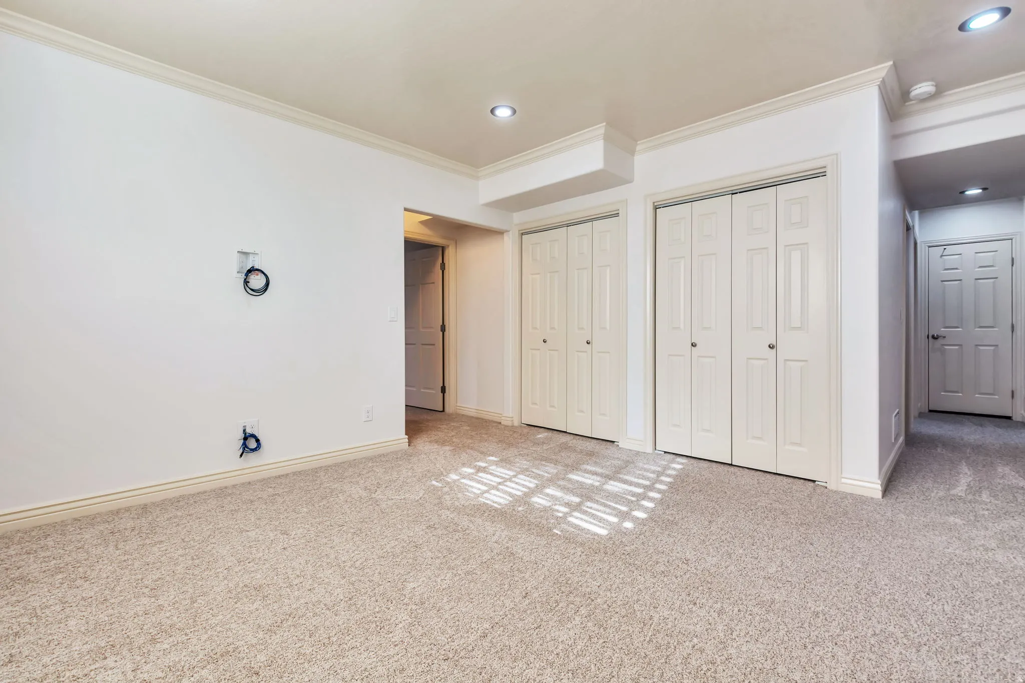 Unfurnished bedroom with two closets, crown molding, carpet flooring, and recessed lighting