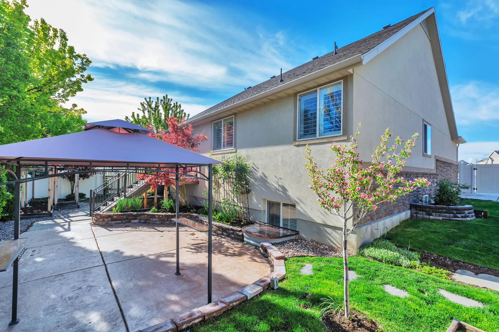 Rear view of property with a gazebo, a patio area, stucco siding, stone siding, and a shingled roof