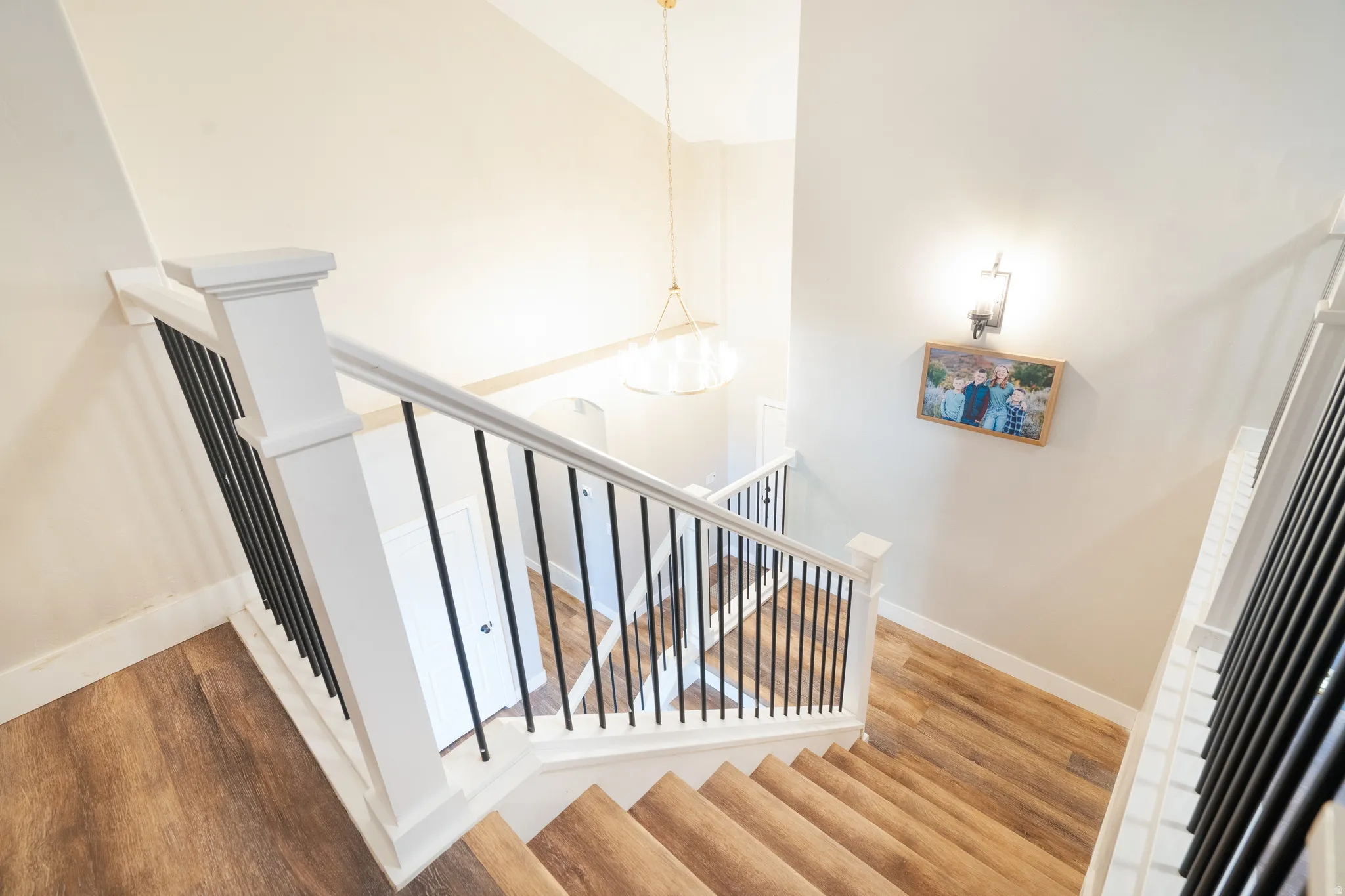 Stairway with wood finished floors, a high ceiling, and hanging lights