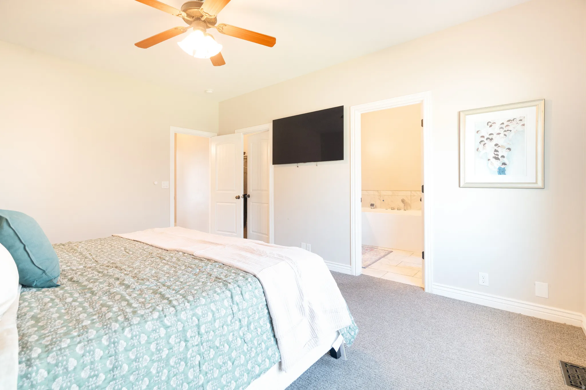 Carpeted bedroom with a ceiling fan and connected bathroom