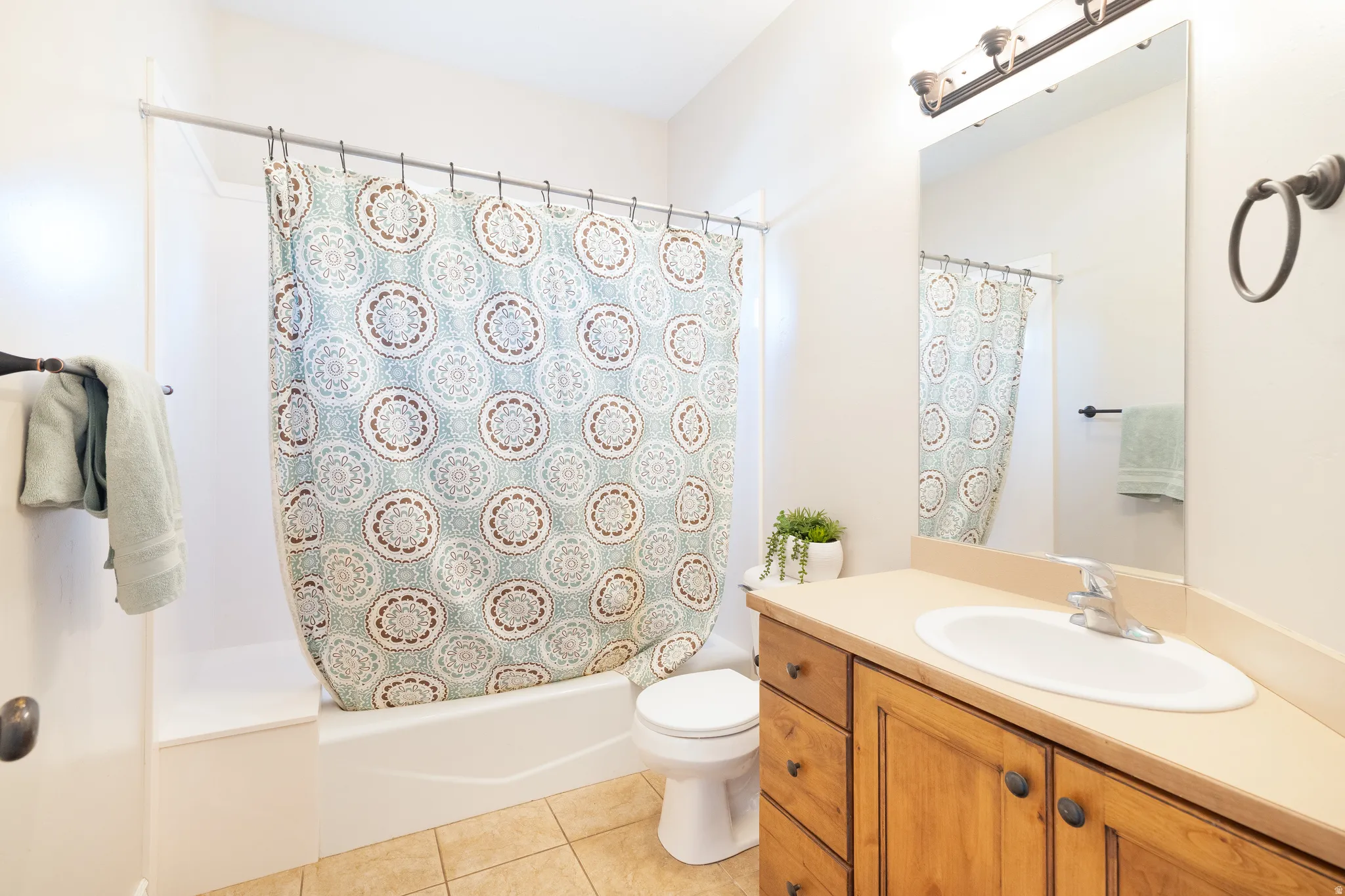 Full bathroom featuring shower / bath combination with curtain, vanity, and light tile patterned floors