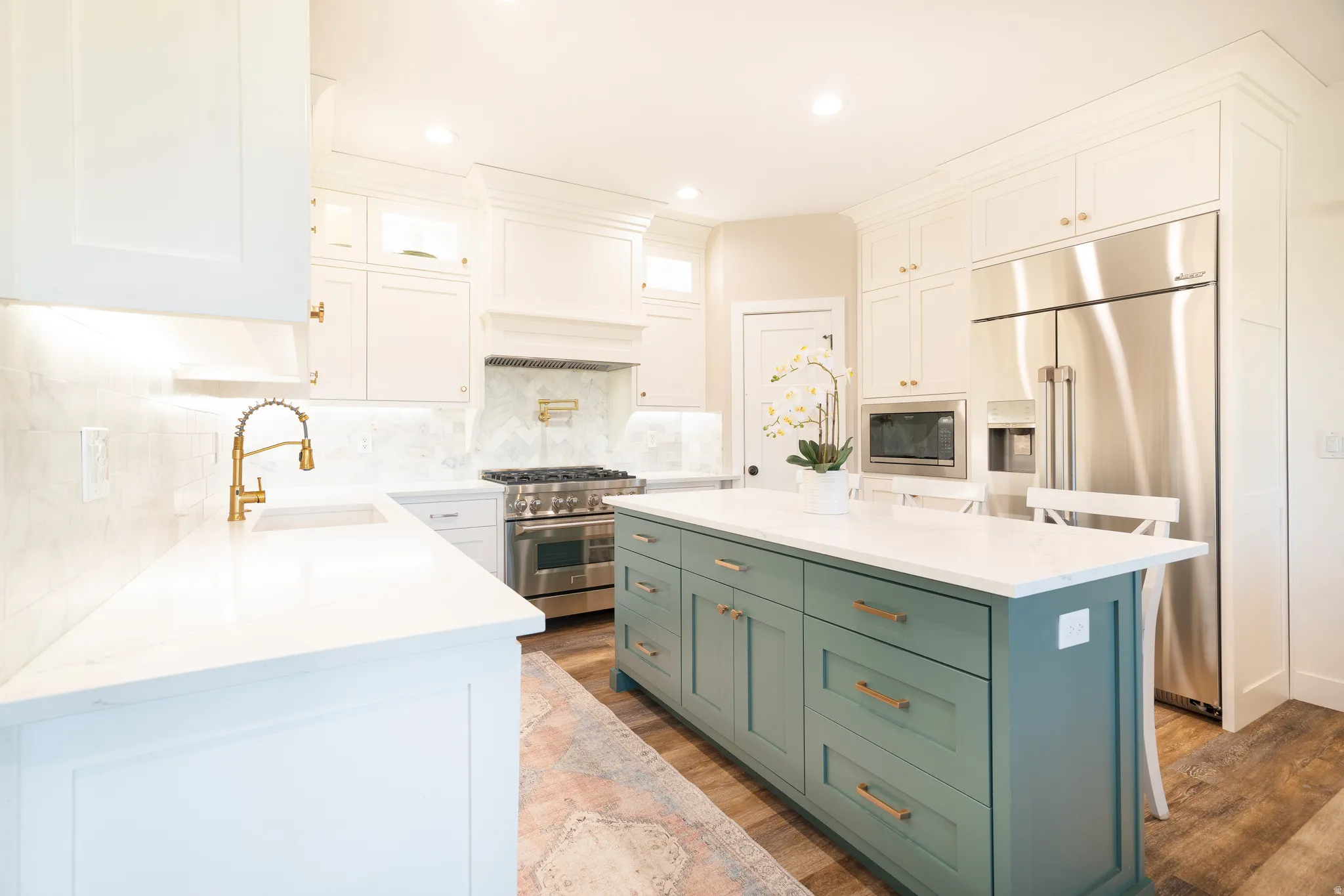 Two tone kitchen featuring two tone cabinets, a center island, high end appliances, light stone countertops, and light wood finished floors