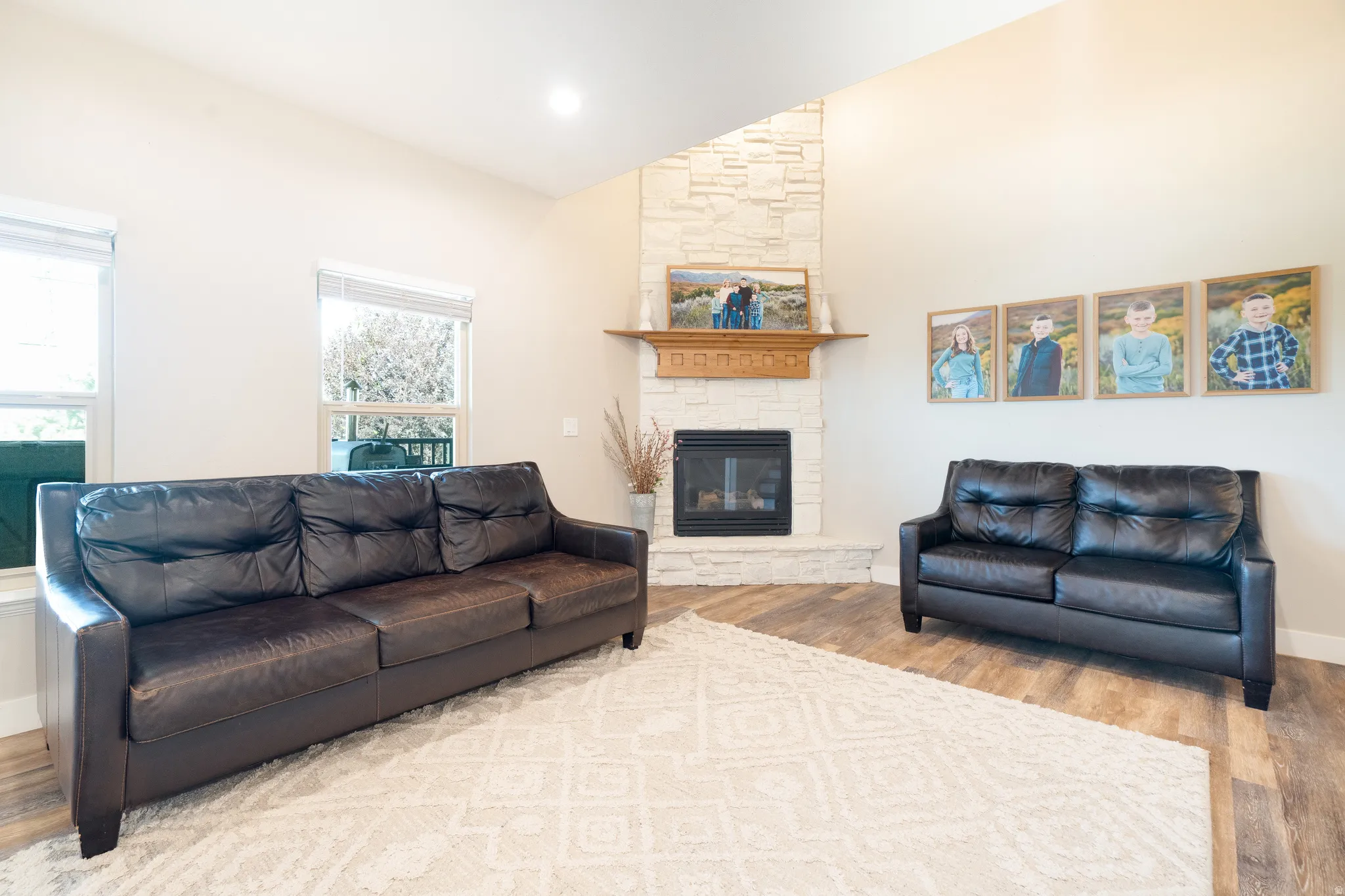 Living area featuring vaulted ceiling, light wood finished floors, a fireplace, and recessed lighting