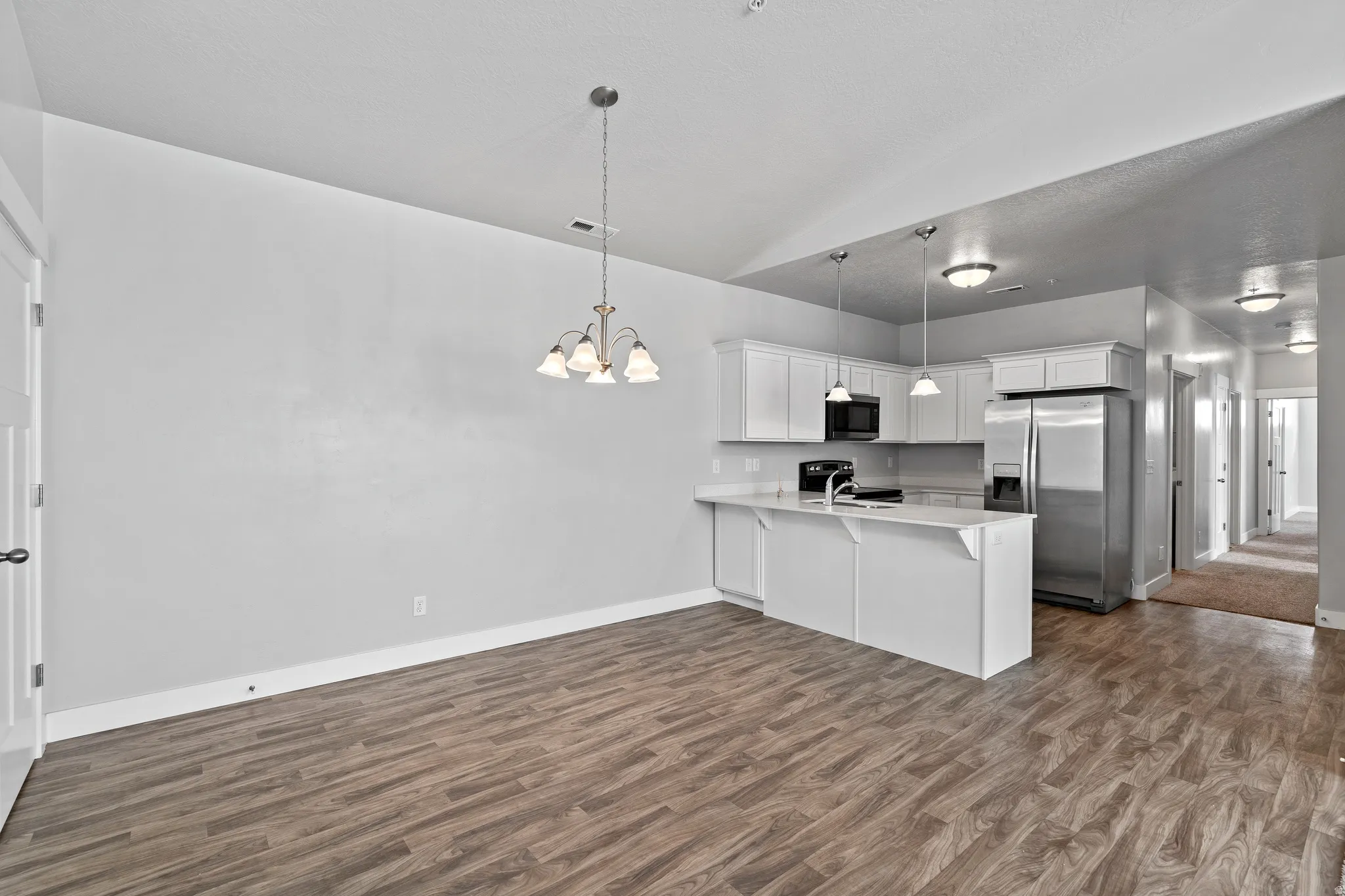 Kitchen featuring black appliances, white cabinetry, a peninsula, and dark wood-style floors