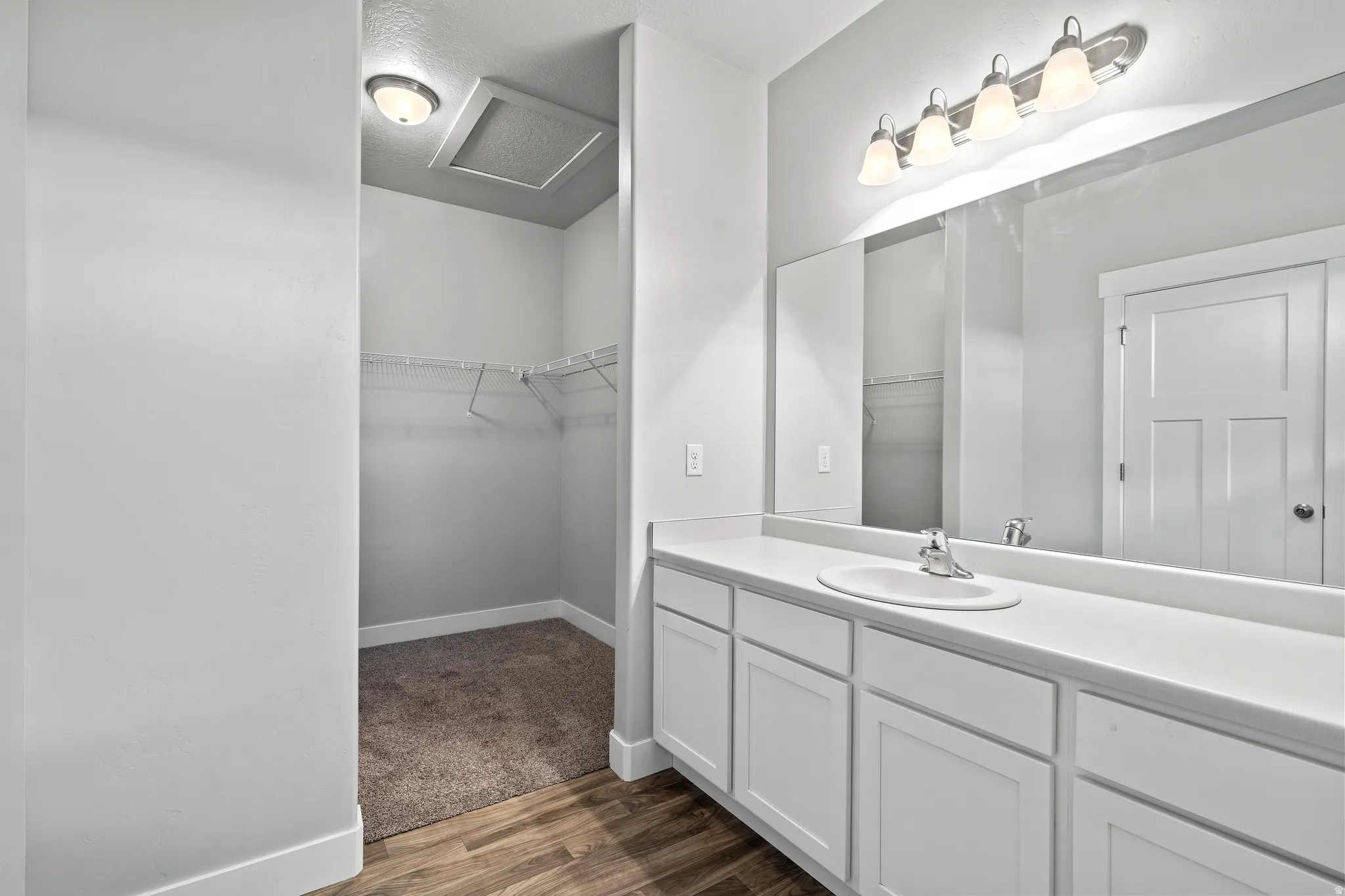 Full bath featuring vanity, dark wood-style flooring, and a walk in closet