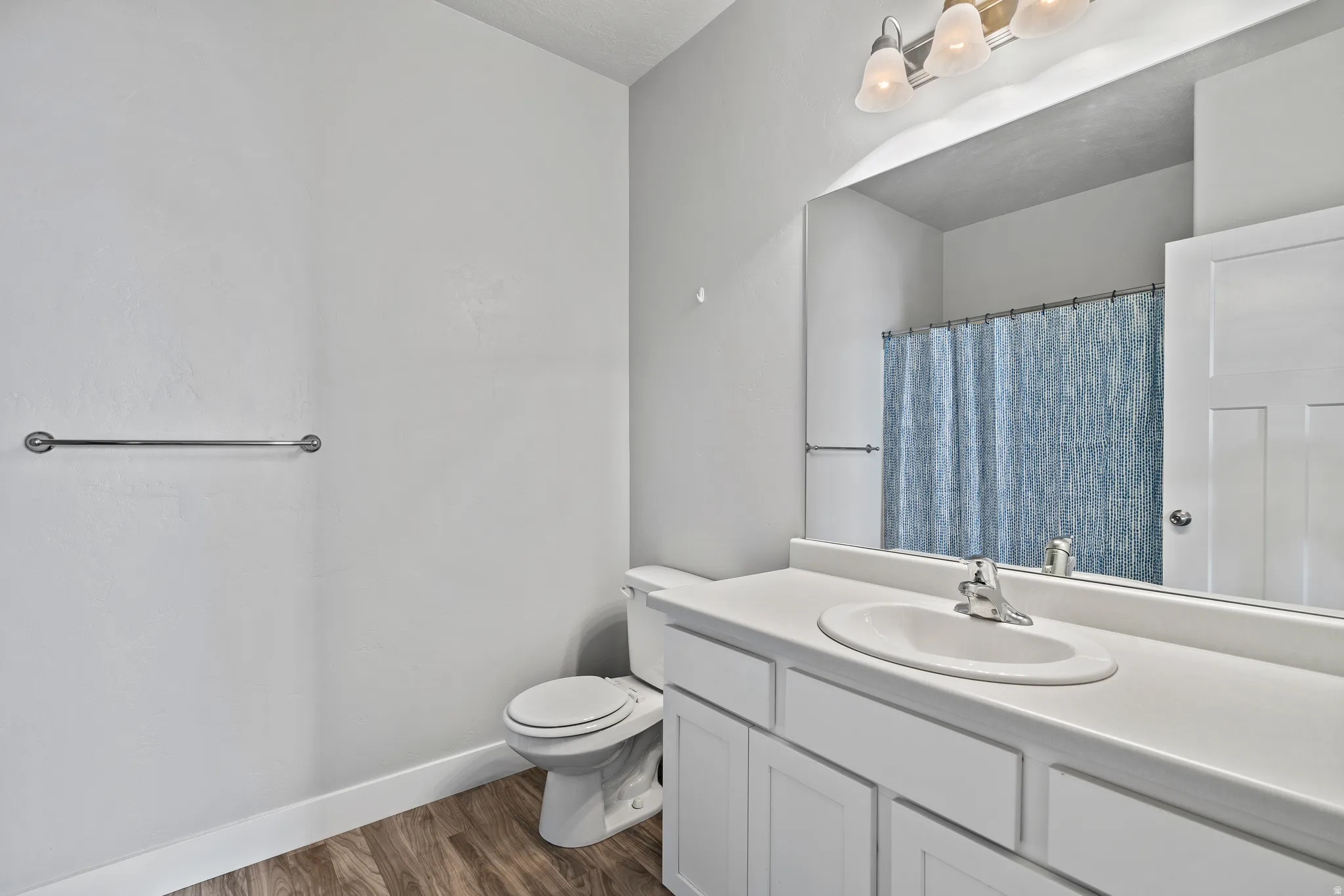 Full bath featuring vanity, curtained shower, and dark wood-type flooring