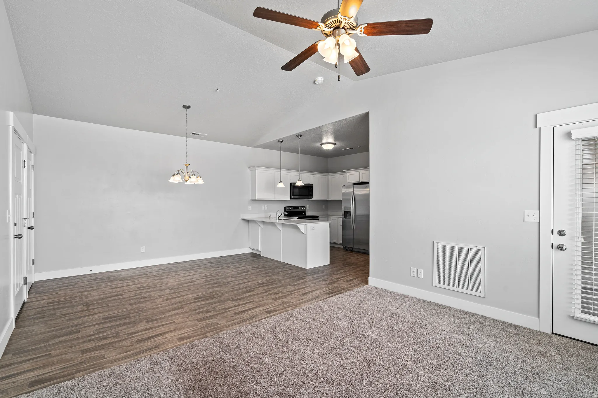Unfurnished living room featuring suspended lighting, ceiling fan, and dark wood-style flooring