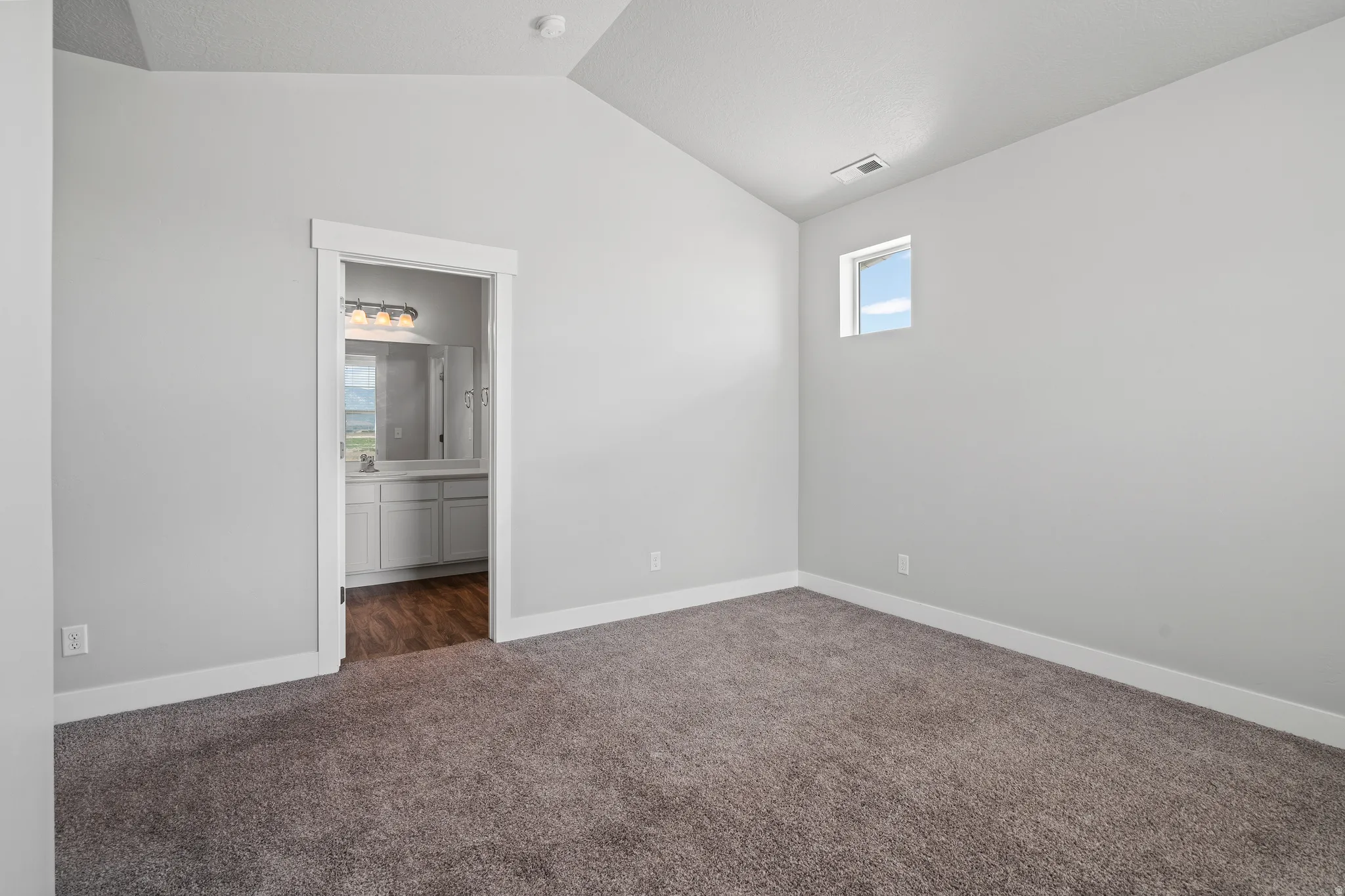 Unfurnished bedroom featuring dark carpet and connected bathroom