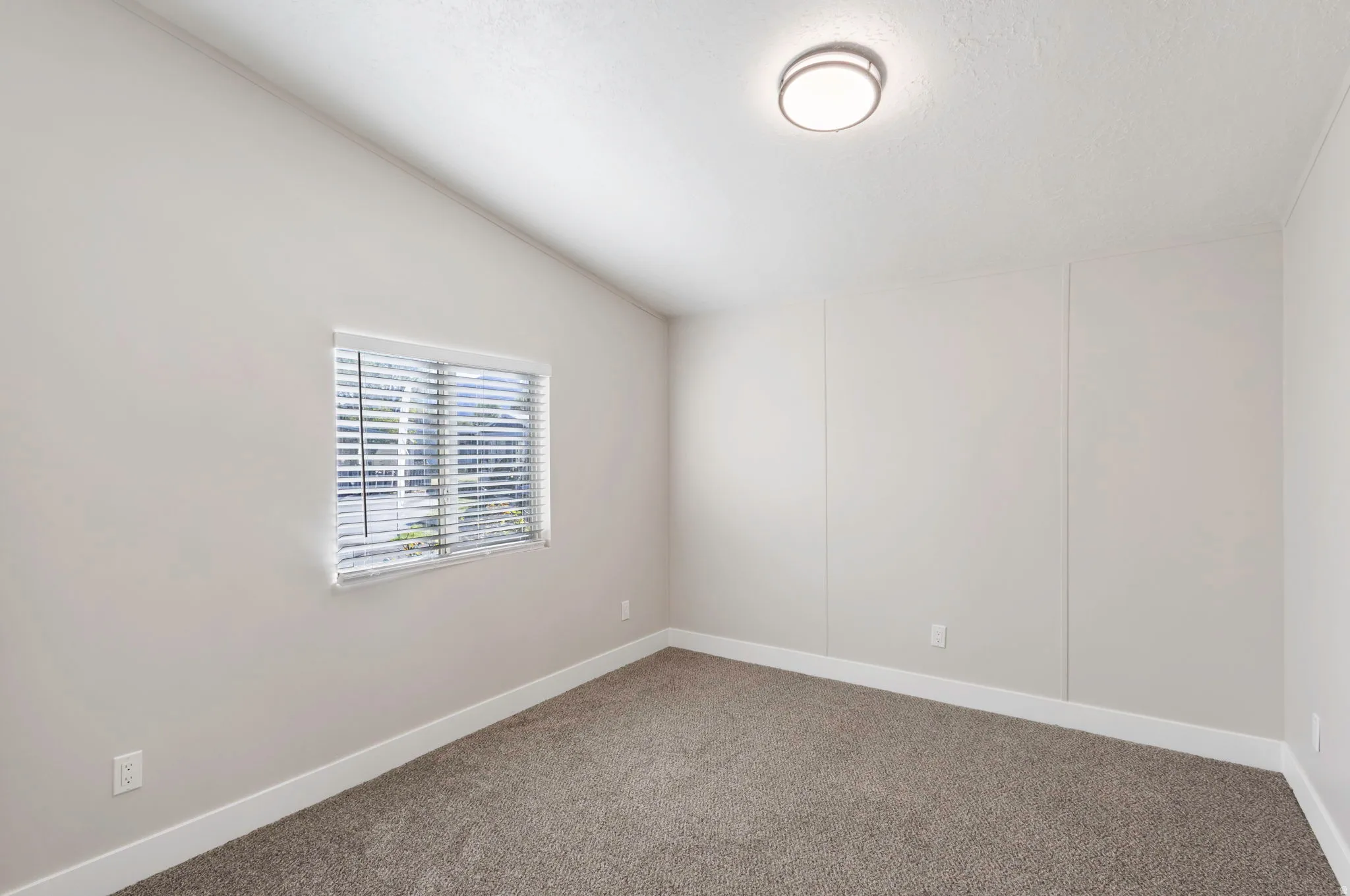 Empty room with vaulted ceiling and carpet