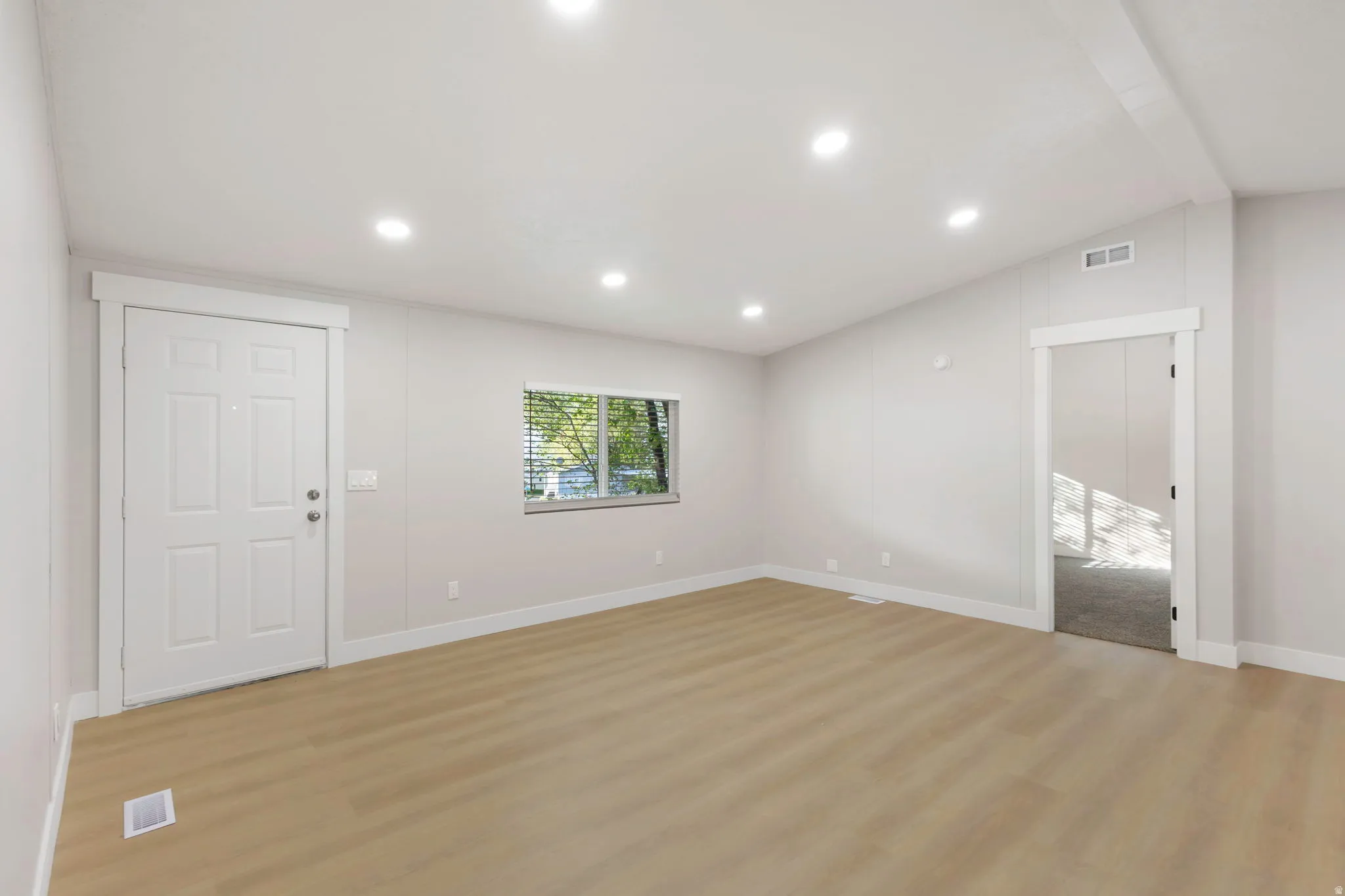 Unfurnished living room with light wood finished floors, lofted ceiling, and recessed lighting