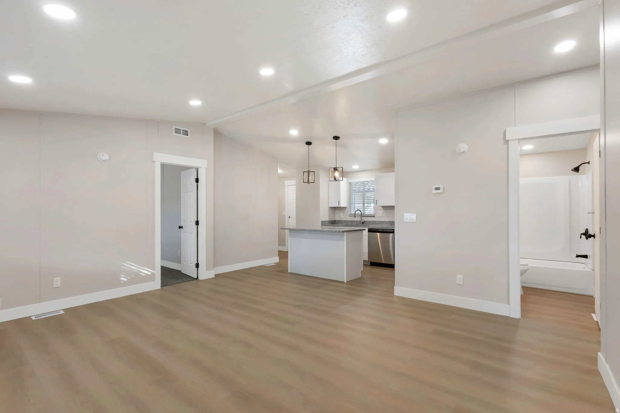 Kitchen with white cabinets, lofted ceiling, open floor plan, a kitchen island, and pendant lighting