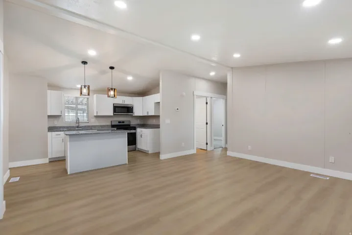 Kitchen featuring stainless steel appliances, white cabinets, a center island, vaulted ceiling, and hanging light fixtures