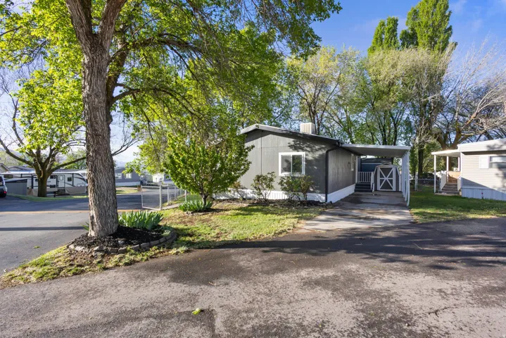 View of front of home with an attached carport, asphalt driveway, and a front lawn