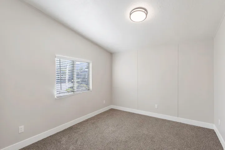 Empty room with vaulted ceiling and carpet