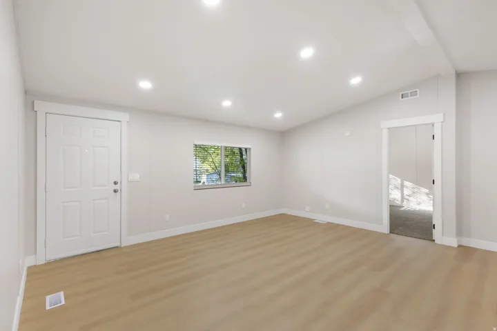 Unfurnished living room with light wood finished floors, lofted ceiling, and recessed lighting