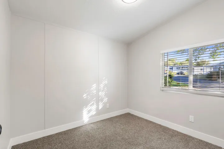 Carpeted empty room featuring vaulted ceiling and baseboards
