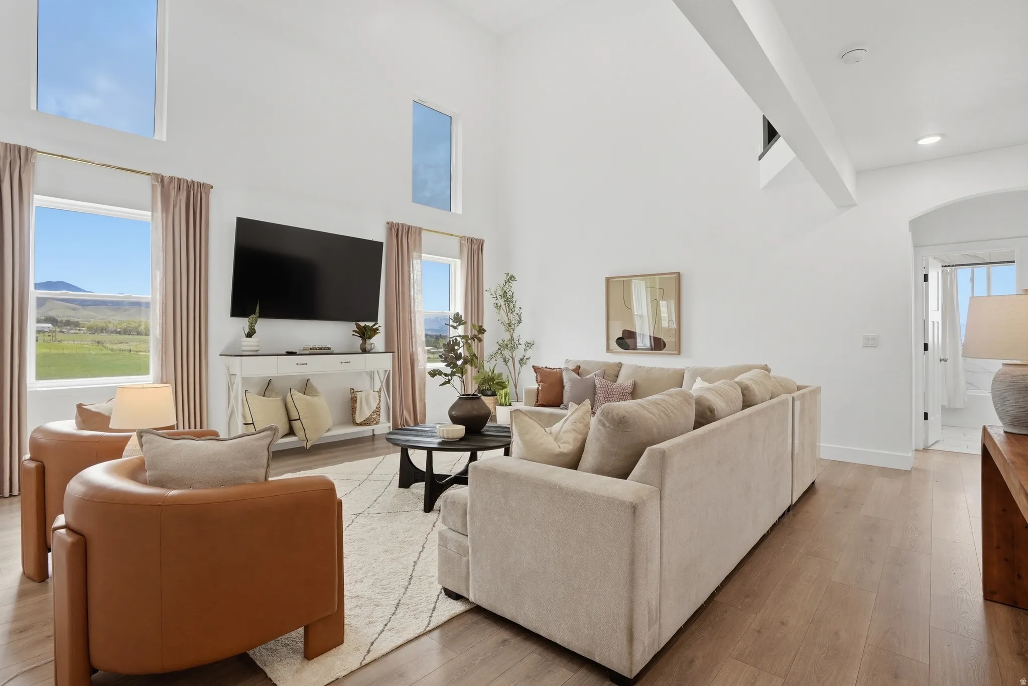 Living room featuring arched walkways, light wood finished floors, healthy amount of natural light, and a high ceiling
