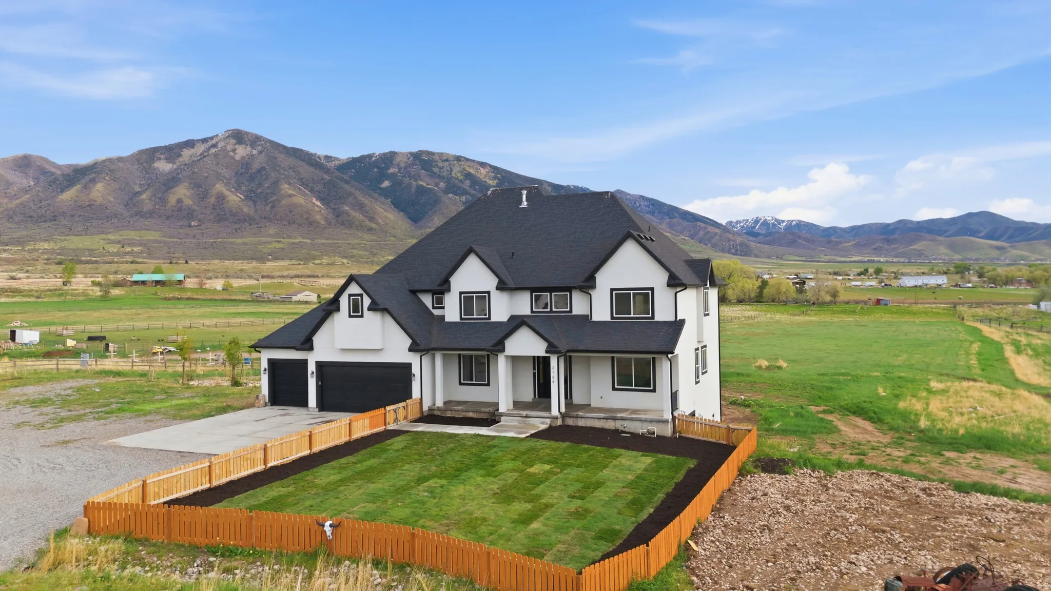 Modern farmhouse featuring stucco siding, driveway, a mountain view, covered porch, and a view of countryside