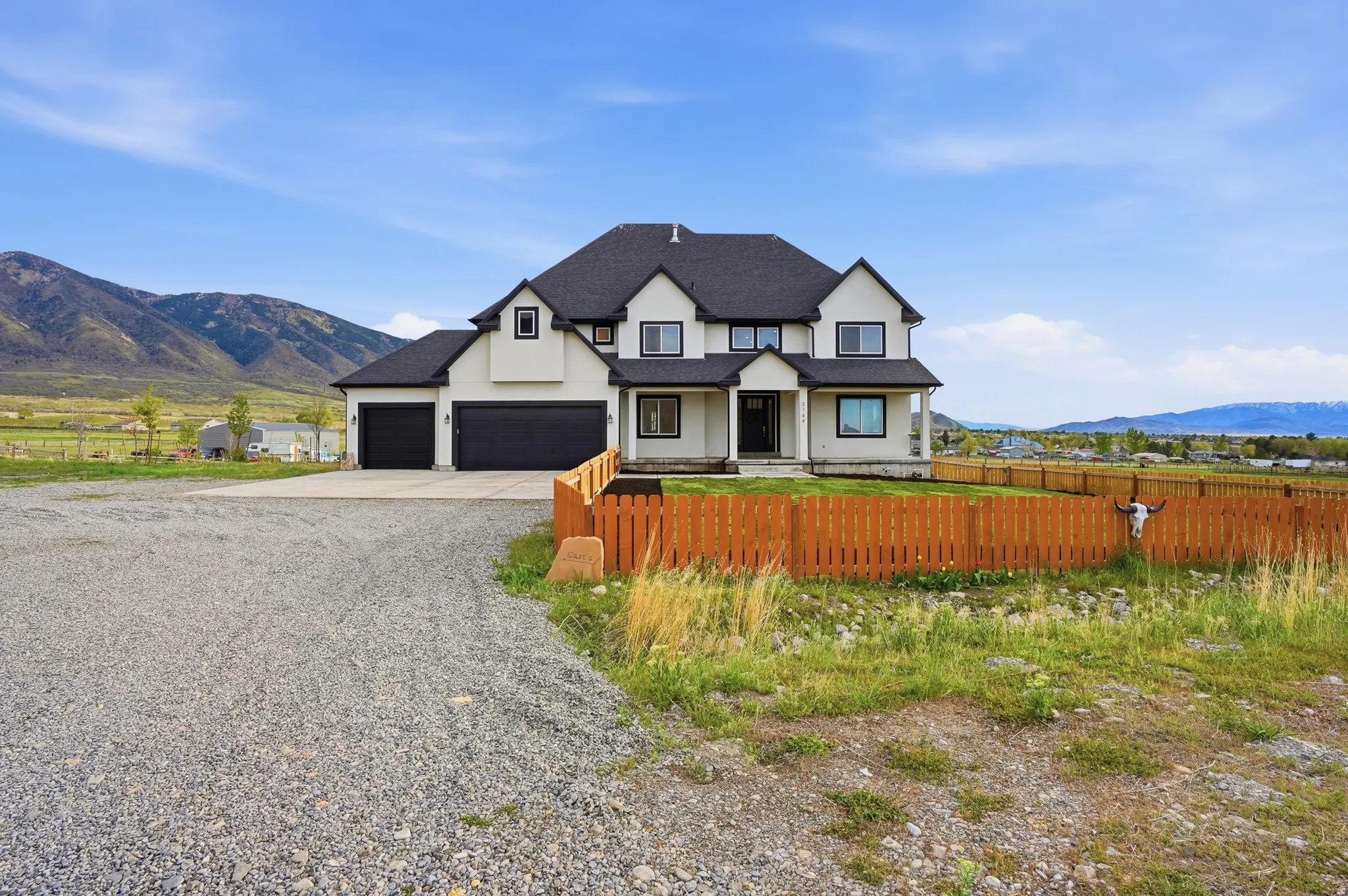 Modern farmhouse style home featuring a mountain view, covered porch, driveway, a shingled roof, and a garage