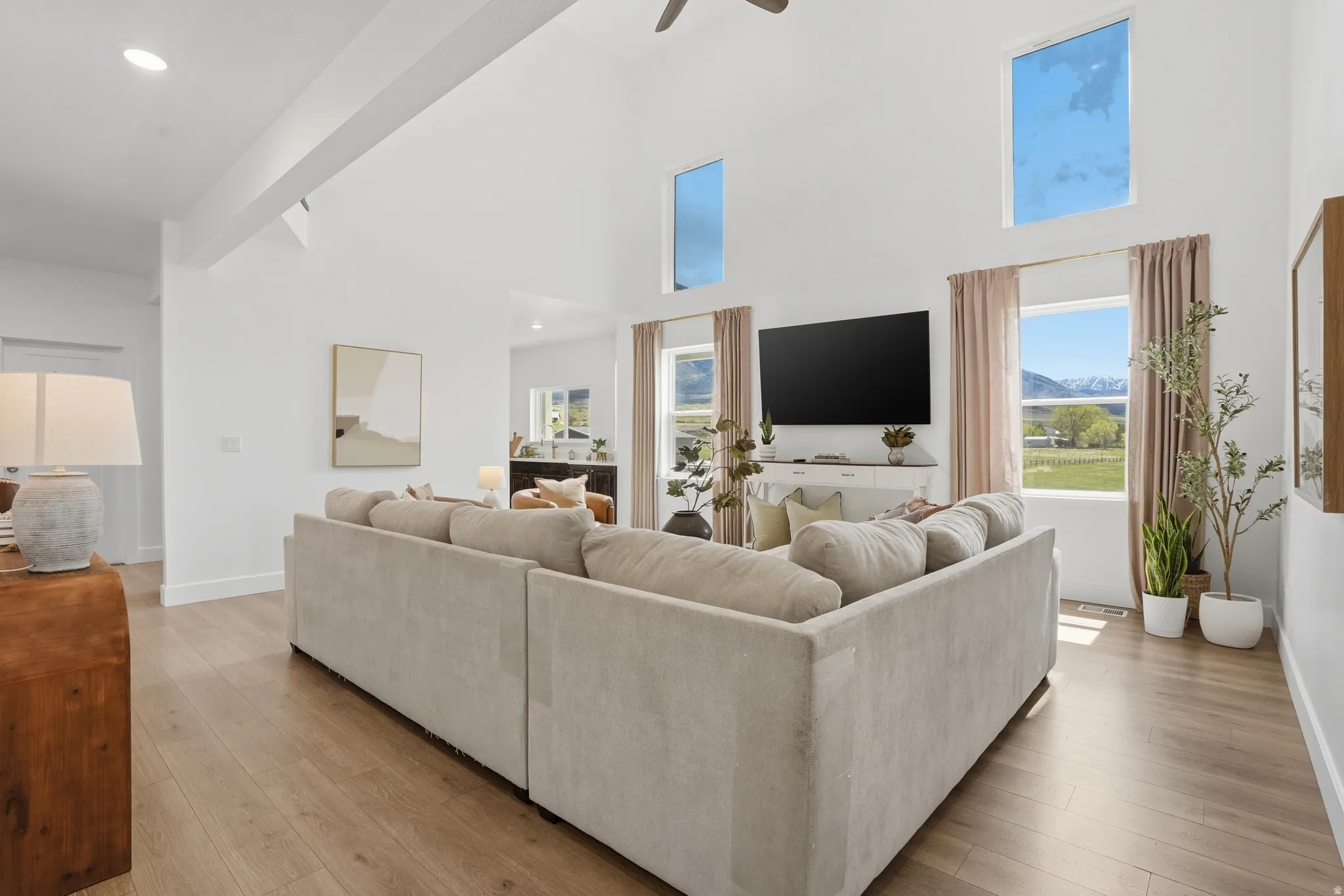 Living room featuring light wood-style floors, a high ceiling, and a ceiling fan