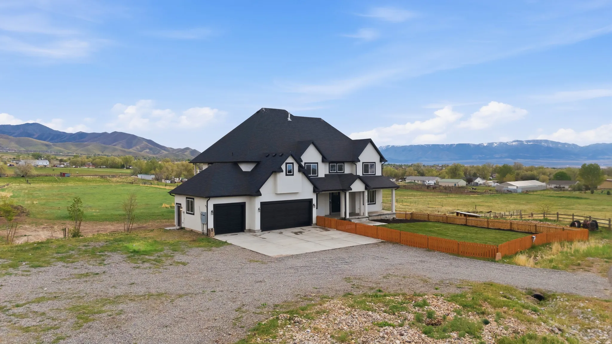 Modern inspired farmhouse featuring a mountain view, concrete driveway, stucco siding, and a view of countryside