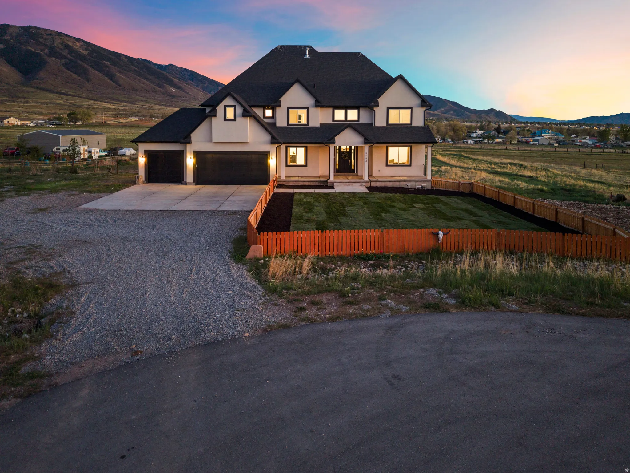 Modern inspired farmhouse with a mountain view, driveway, a fenced front yard, covered porch, and stucco siding