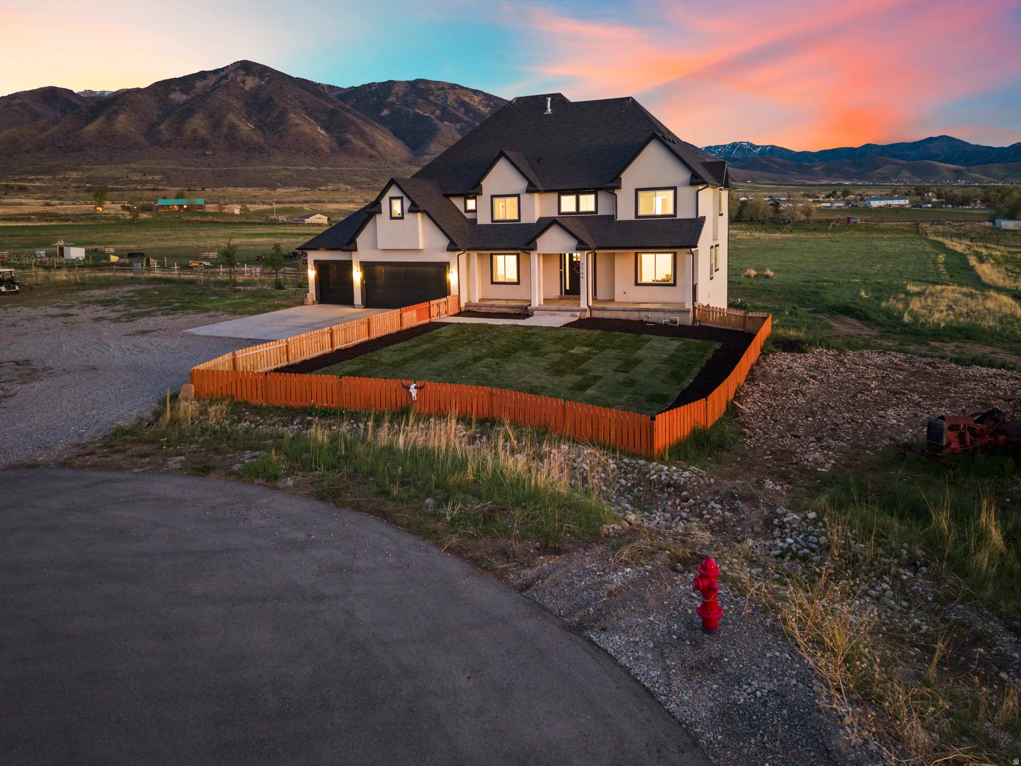 Modern farmhouse with gravel driveway, a mountain view, a garage, stucco siding, and a yard
