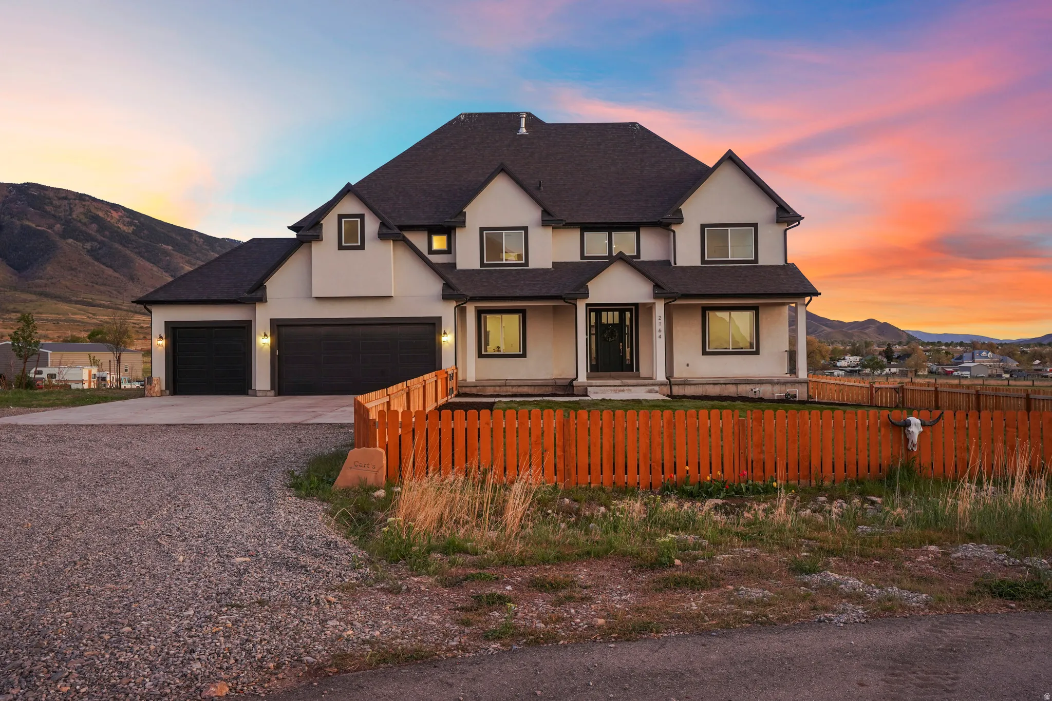 View of front of property featuring a mountain view, a fenced front yard, covered porch, driveway, and stucco siding
