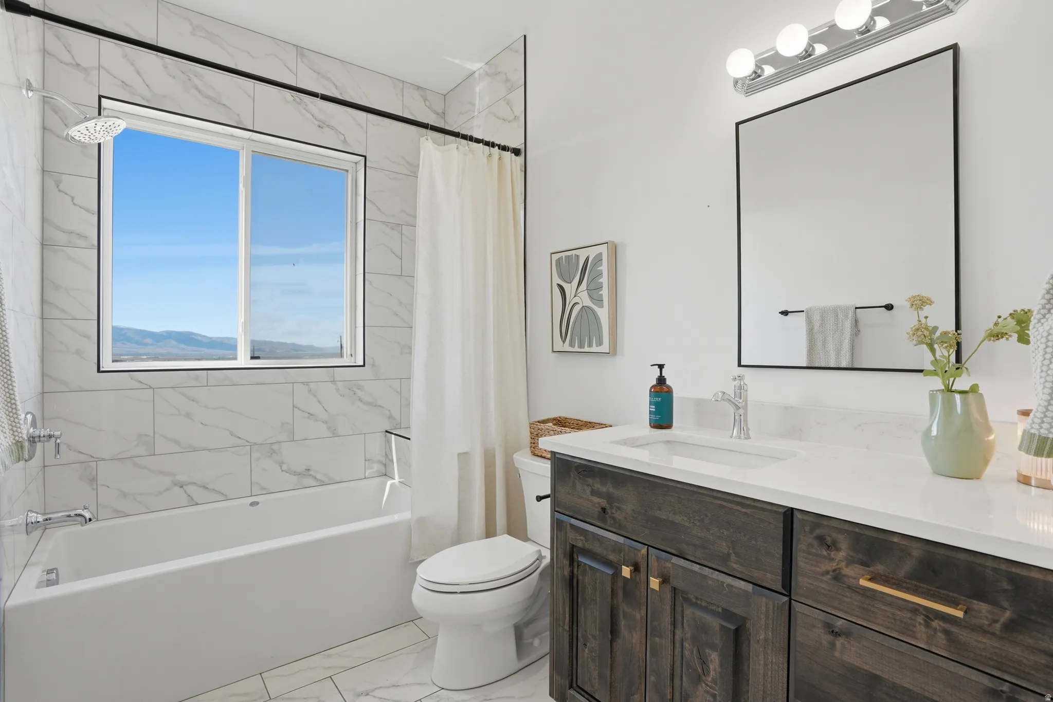 Full bath with vanity, light marble finish flooring, and shower / bath combo