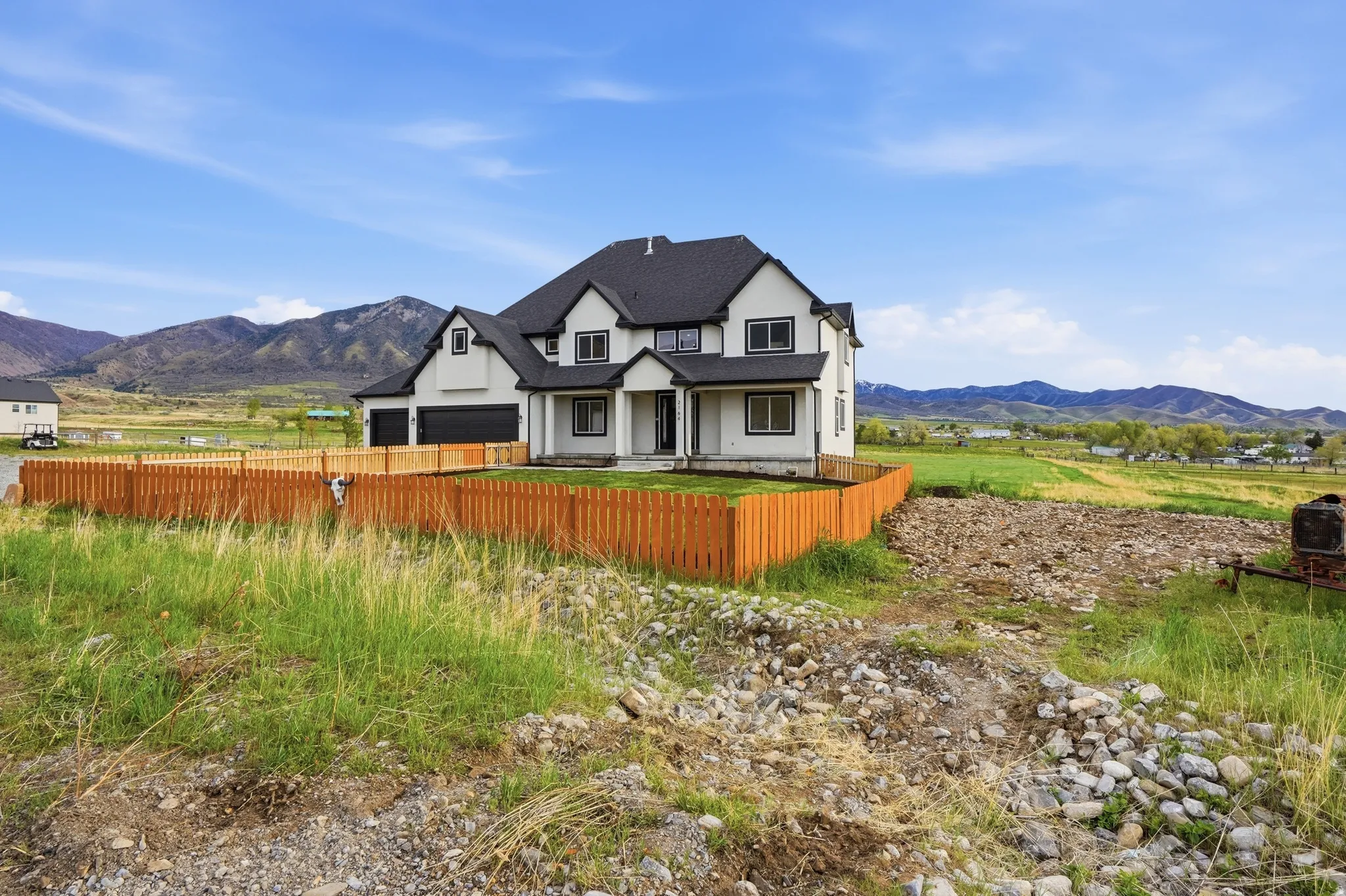 Modern farmhouse featuring a mountain view, stucco siding, a garage, and a porch