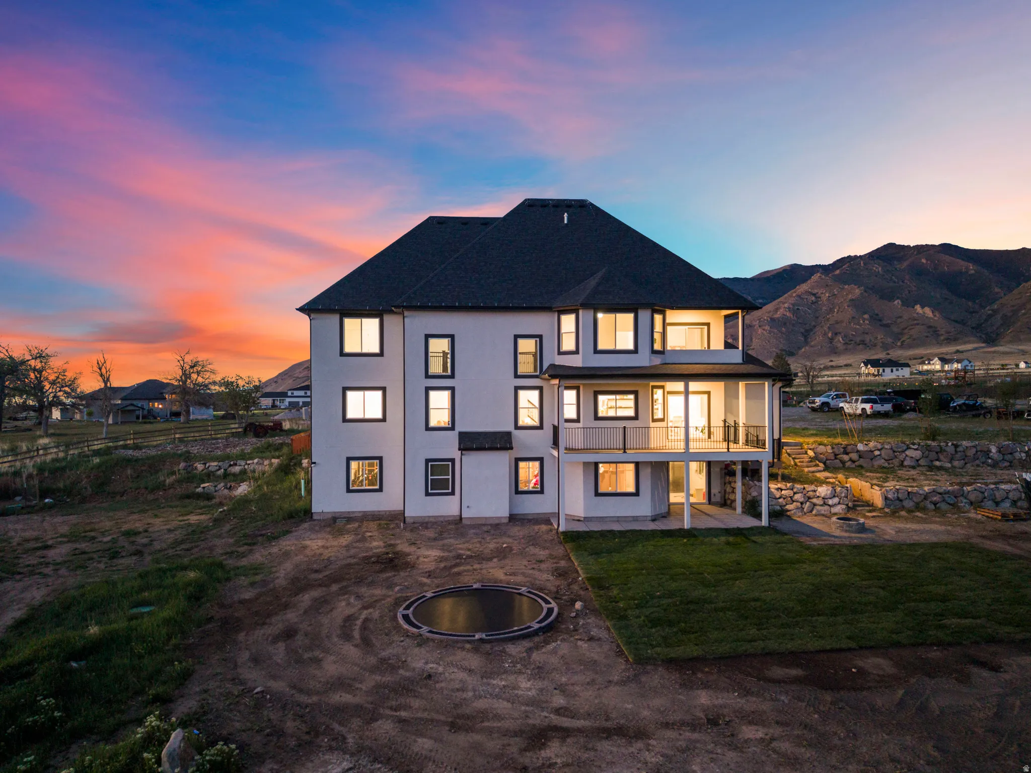 Rear view of property with a patio area, stucco siding, a lawn, a balcony, and a mountain view