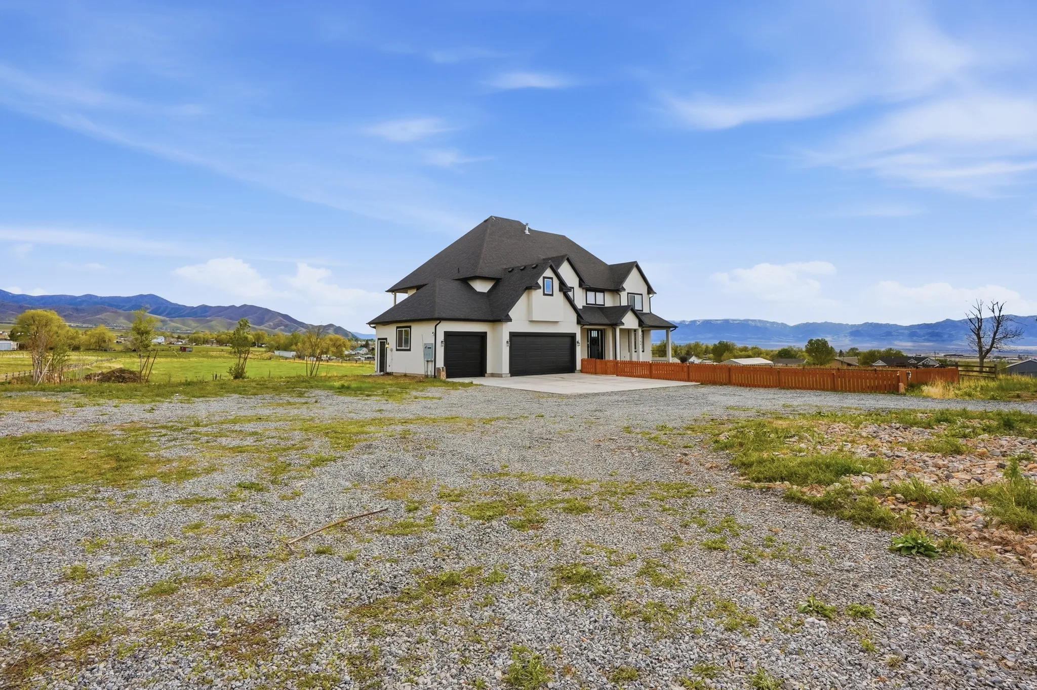 View of front of home with a mountain view, gravel driveway, stucco siding, and a patio