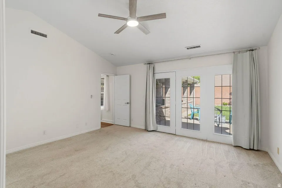 Spare room featuring light carpet, a ceiling fan, and vaulted ceiling