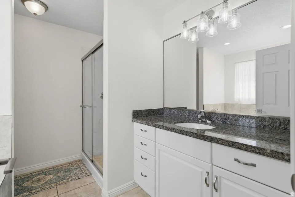 Bathroom with vanity, a stall shower, light tile patterned floors, and recessed lighting