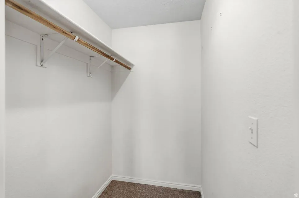Walk in closet with dark colored carpet