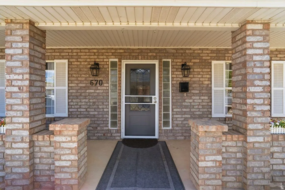 Entrance to property with covered porch and brick siding