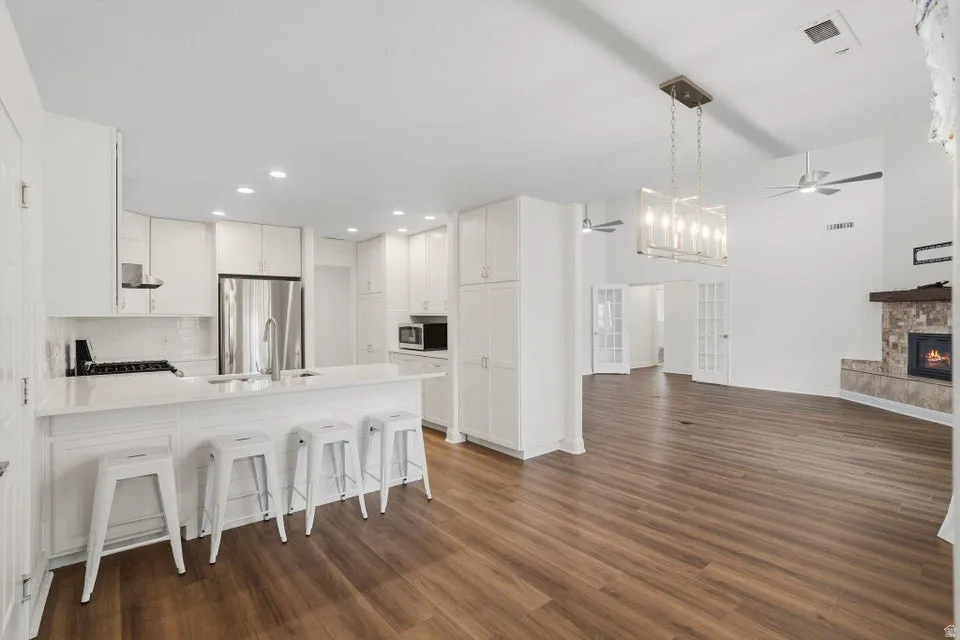 Kitchen featuring a ceiling fan, a kitchen bar, open floor plan, a stone fireplace, and a peninsula