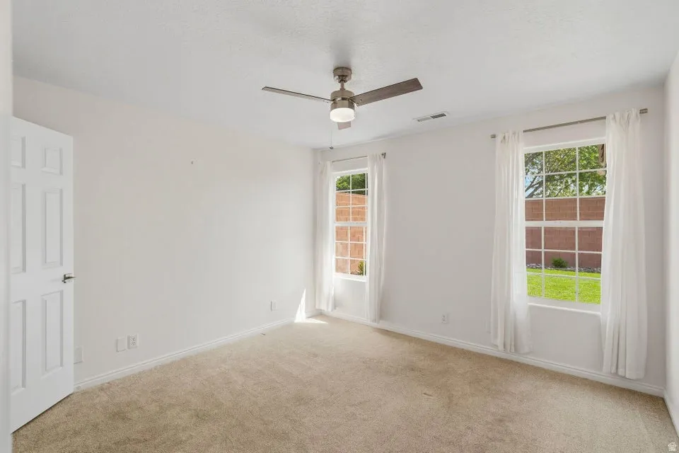 Unfurnished room featuring light colored carpet and ceiling fan
