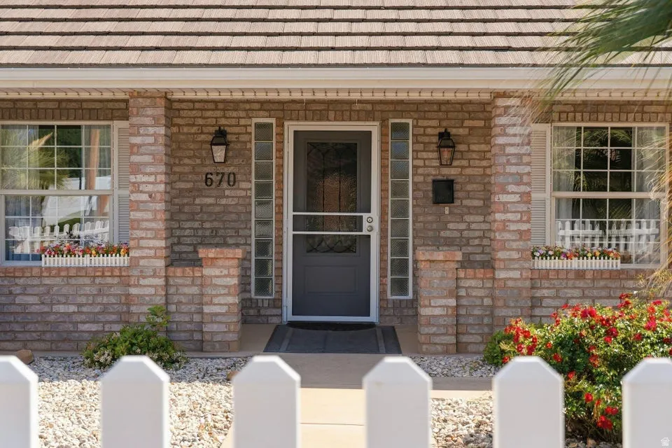 View of exterior entry featuring covered porch and brick siding