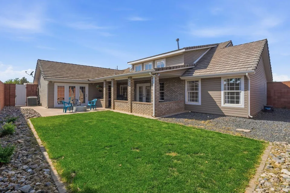 Rear view of house featuring a patio area, a fenced backyard, brick siding, and a gate