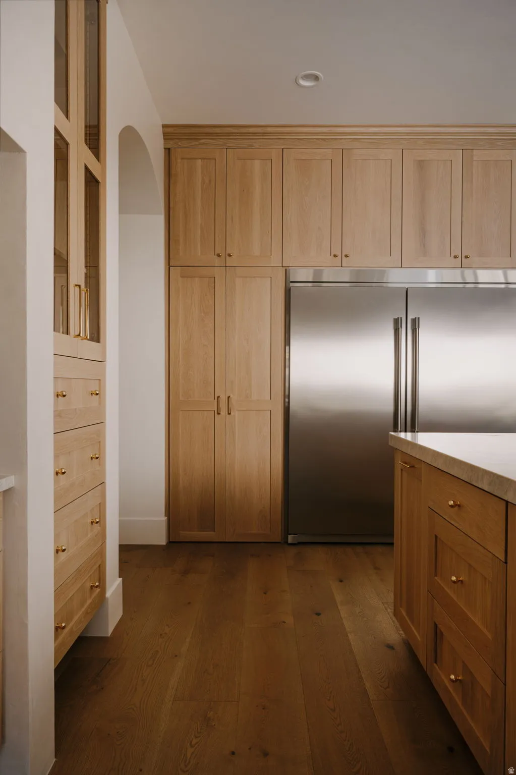 Kitchen featuring built in refrigerator, dark wood-style floors, arched walkways, and wood finish cabinetry