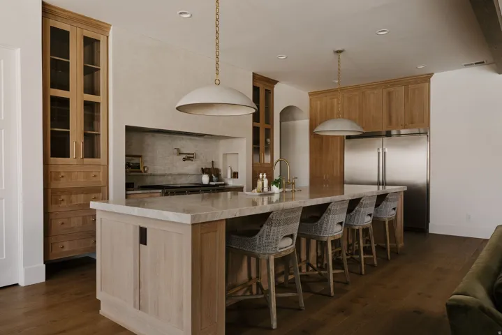 Kitchen featuring glass insert cabinets, stainless steel built in refrigerator, backsplash, dark wood-type flooring, and a large island with sink