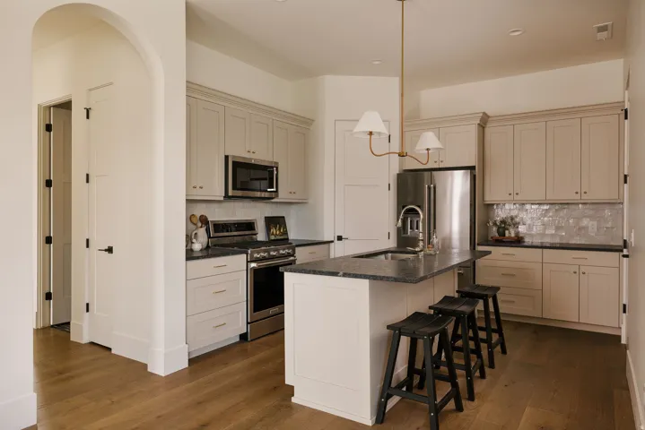 Casita Kitchen featuring stainless steel appliances, a center island with sink, dark wood finished floors, Leathered granite countertops and a breakfast bar