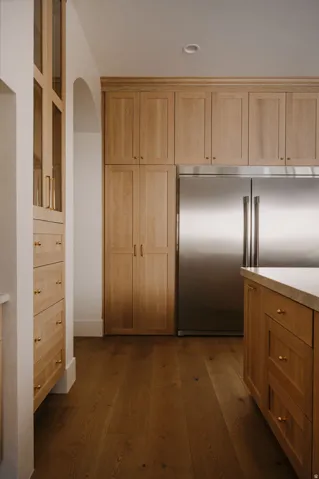 Kitchen featuring built in refrigerator, dark wood-style floors, arched walkways, and wood finish cabinetry