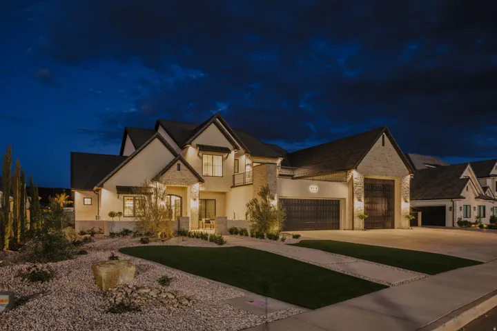 View of front facade with stone siding, stucco siding, and concrete driveway