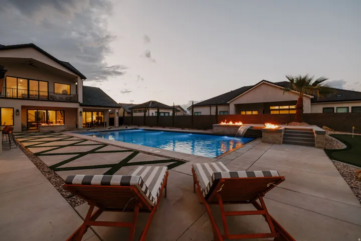 Pool at dusk featuring a patio, a fenced backyard, and a balcony