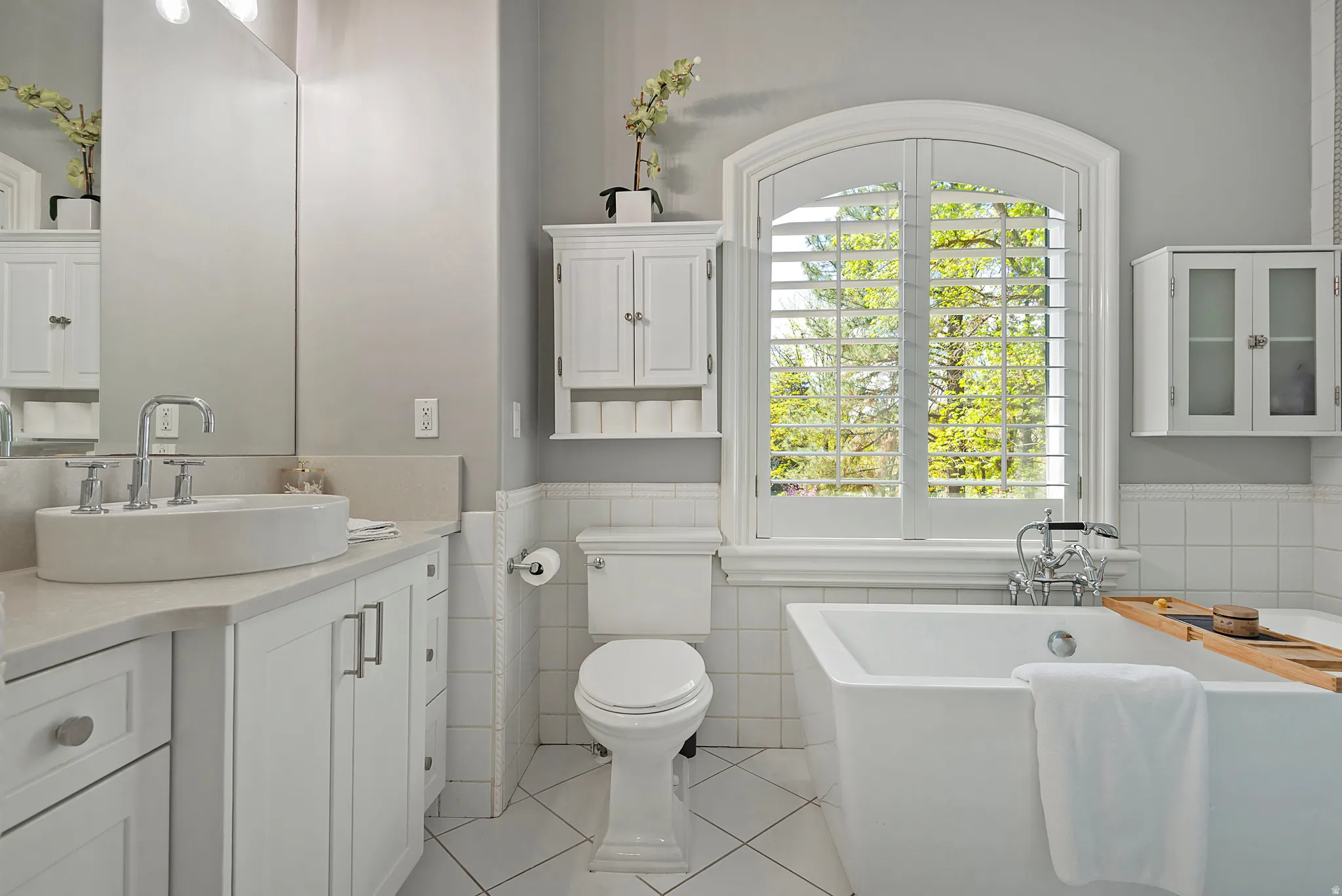 Bathroom with vanity, wainscoting, a soaking tub, light tile patterned flooring, tile walls, and glass shower
