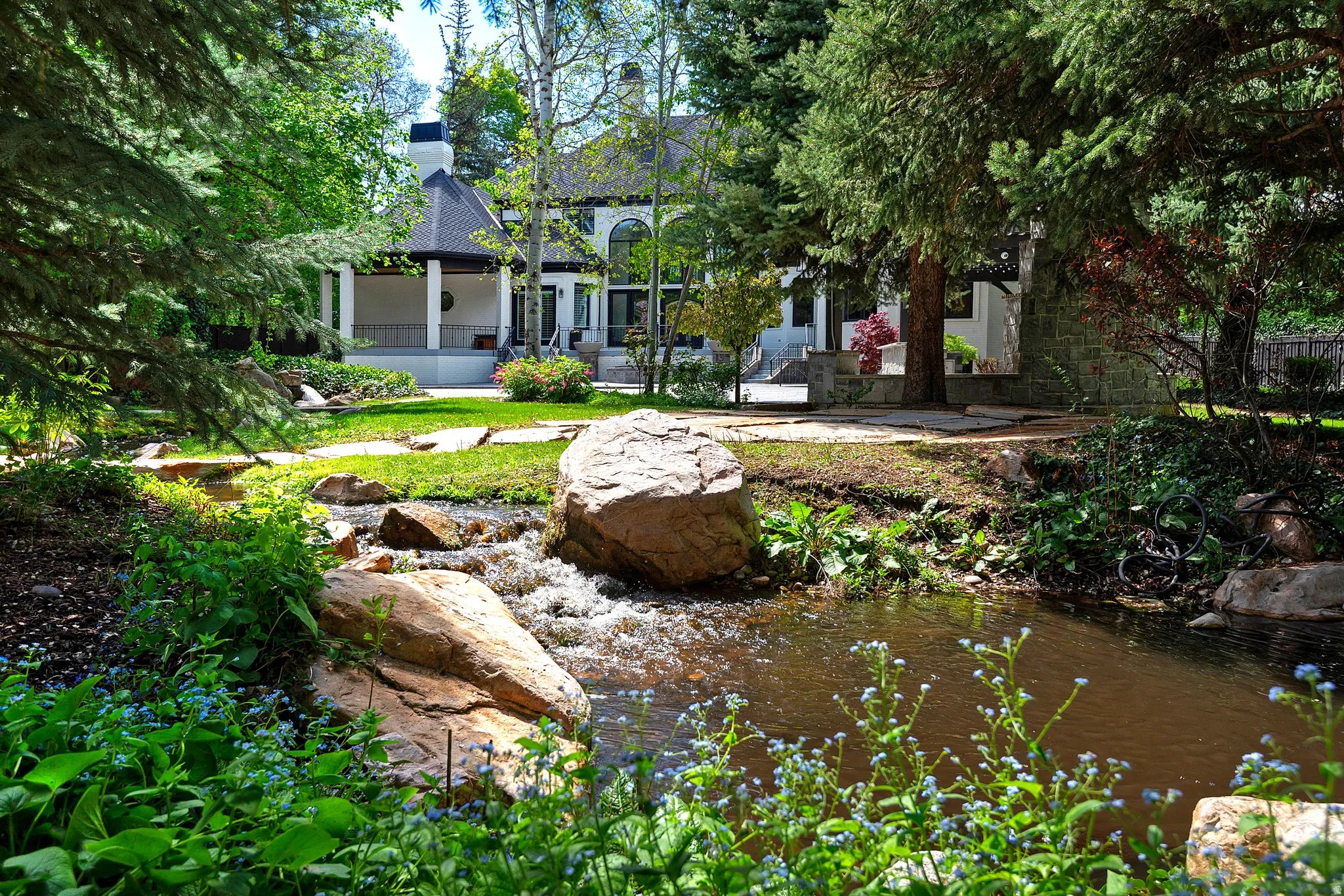 View of yard featuring a ponds, stream, meandering pathways and a pool