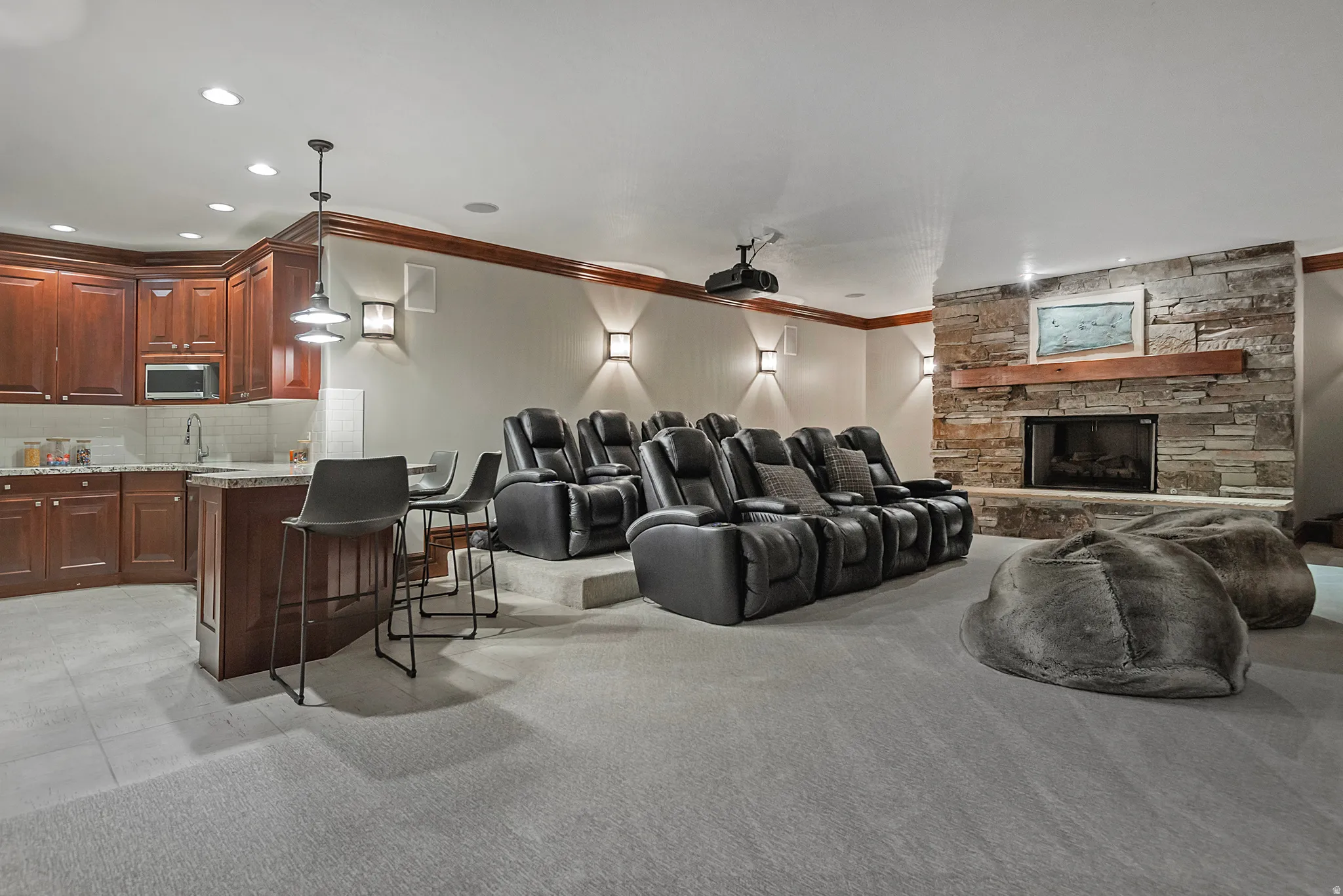 Cinema room with crown molding, light colored carpet, recessed lighting, and a stone fireplace