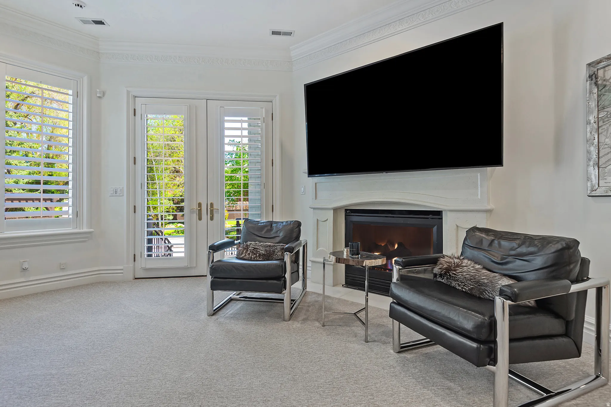 Living area featuring french doors, light colored carpet, crown molding, and a gas fireplace
